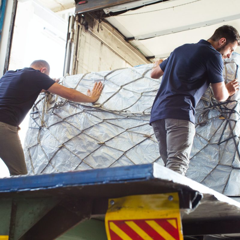 Workers pushing freight into air freight container